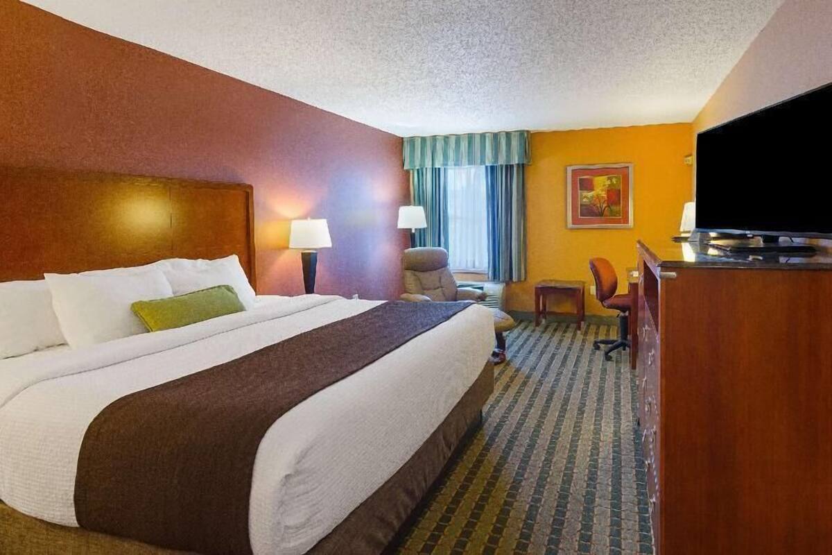Una habitación de hotel con una cama grande, dos lámparas de noche, un televisor, un escritorio y una silla.
