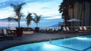 A poolside area with lounge chairs and potted plants, overlooking a body of water. - The Cliffs Hotel and Spa (Pismo Beach)