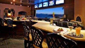 A restaurant with a view of the ocean, multiple screens, and a bar area. - The Cliffs Hotel and Spa (Pismo Beach)