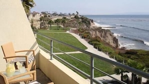 A balcony with a view of the ocean, a chair, and a table with a glass of drink. - The Cliffs Hotel and Spa (Pismo Beach)