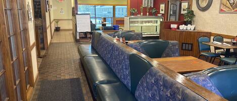 A restaurant interior with high wooden ceilings, a central counter, and seating with patterned upholstery.