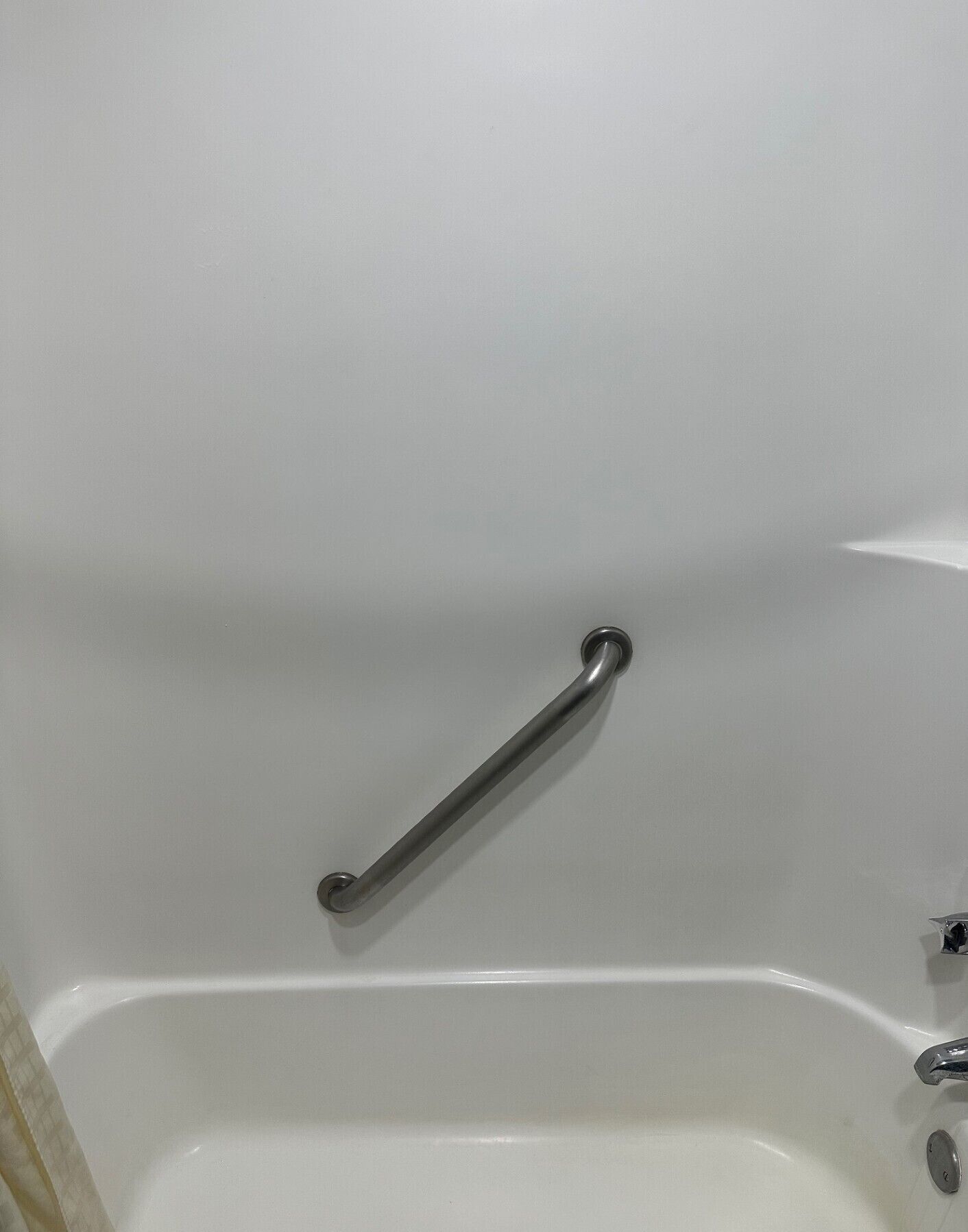 A white bathtub with a grab bar installed on the wall.