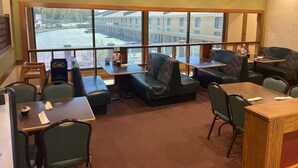 A restaurant with high tables and booths, large windows offering a view of the street, and a patterned carpet. - Super 8 by Wyndham Fort Scott (Fort Scott)