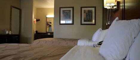 Una habitación de hotel con dos camas, un aparador, un espejo y cuadros en la pared.