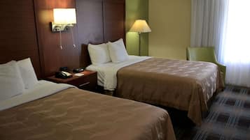 Habitació d'hotel amb dos llits, una tauleta de nit amb un telèfon, una làmpada i una cadira.