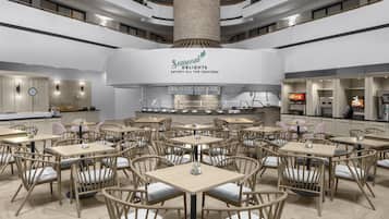 A spacious dining area with multiple tables and chairs, a central counter with a menu, and a large pillar.