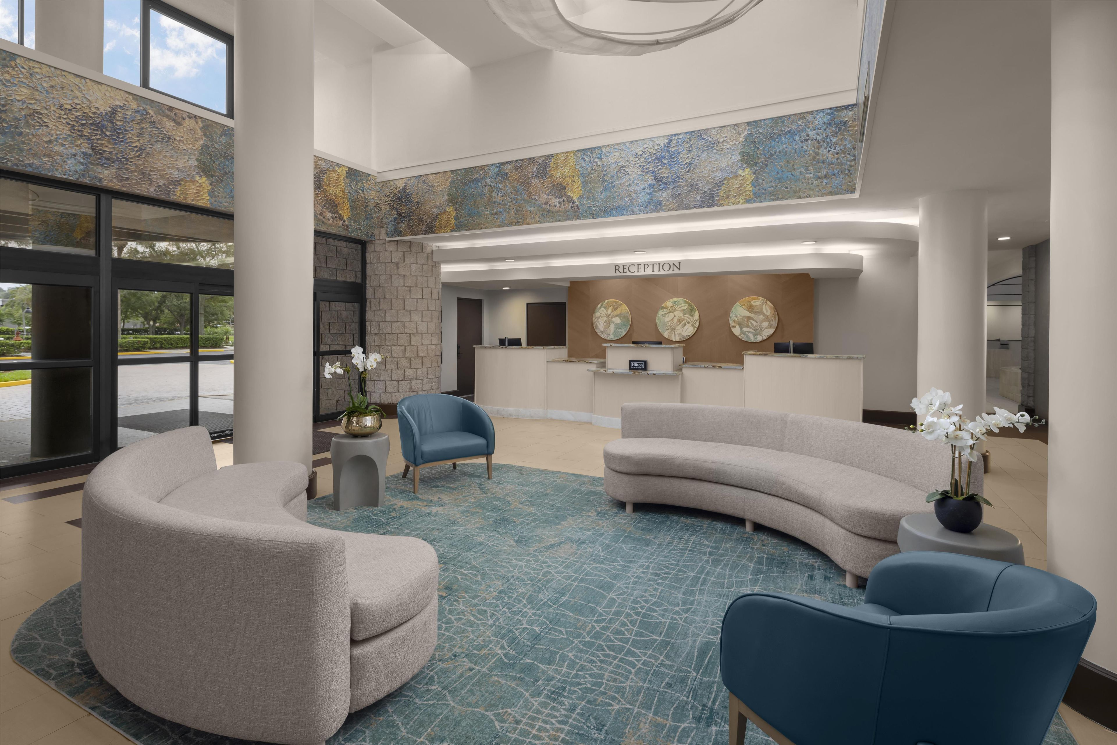 A hotel reception area with a curved sofa, a blue armchair, and a reception desk.