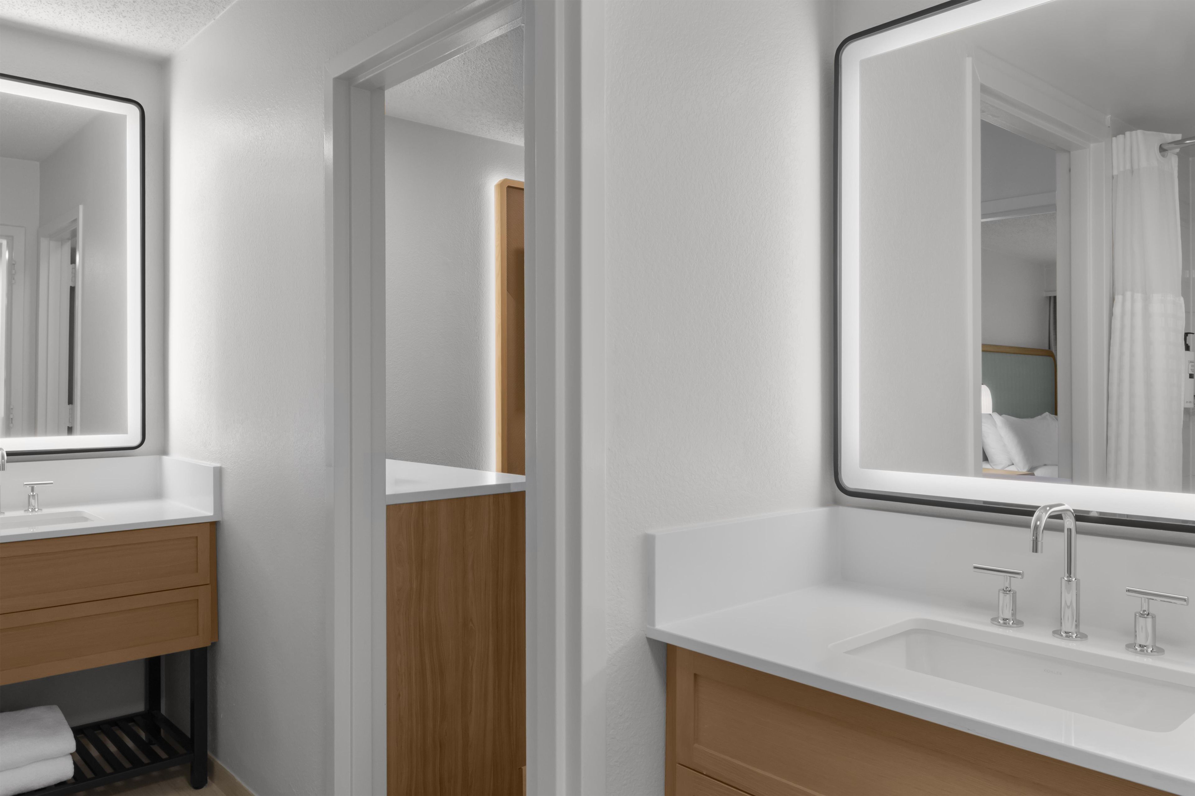 A modern bathroom with a white vanity, a mirror, and a shower area.