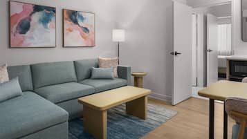 A modern living room with a sectional sofa, a coffee table, a floor lamp, and abstract wall art.
