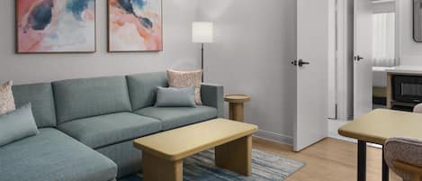 A modern living room with a sectional sofa, a coffee table, a floor lamp, and abstract wall art.