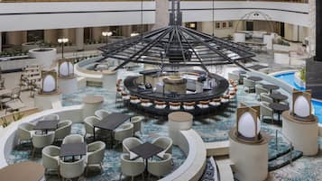 A spacious indoor atrium with multiple seating areas, a central fountain, and a pool.