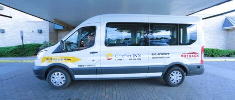 A white van with "Comfort Inn" and "Outback Steakhouse" logos, parked in front of a building.