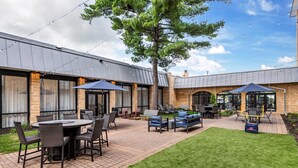A patio area with outdoor seating, a lawn, and a building with large windows and a brick facade. - Comfort Inn MSP Airport - Mall of America (Bloomington)
