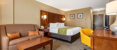 A hotel room with a bed, a sofa, a desk, and a chair.
