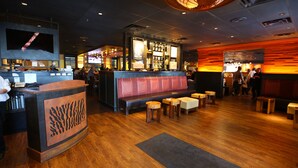 A restaurant interior with a bar area, wooden flooring, and a seating section with tables and benches. - Comfort Inn MSP Airport - Mall of America (Bloomington)