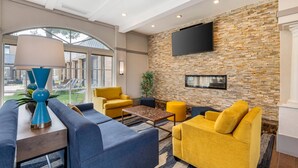 A modern living room with a stone wall, a flat-screen TV, and a large window. - Comfort Inn MSP Airport - Mall of America (Bloomington)