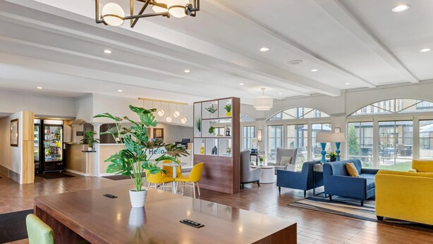 A spacious hotel lobby with a wooden reception desk, seating area with yellow chairs, and a blue sofa. - Comfort Inn MSP Airport - Mall of America (Bloomington)