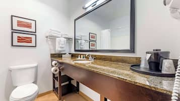 A modern bathroom with a toilet, sink, and large mirror.