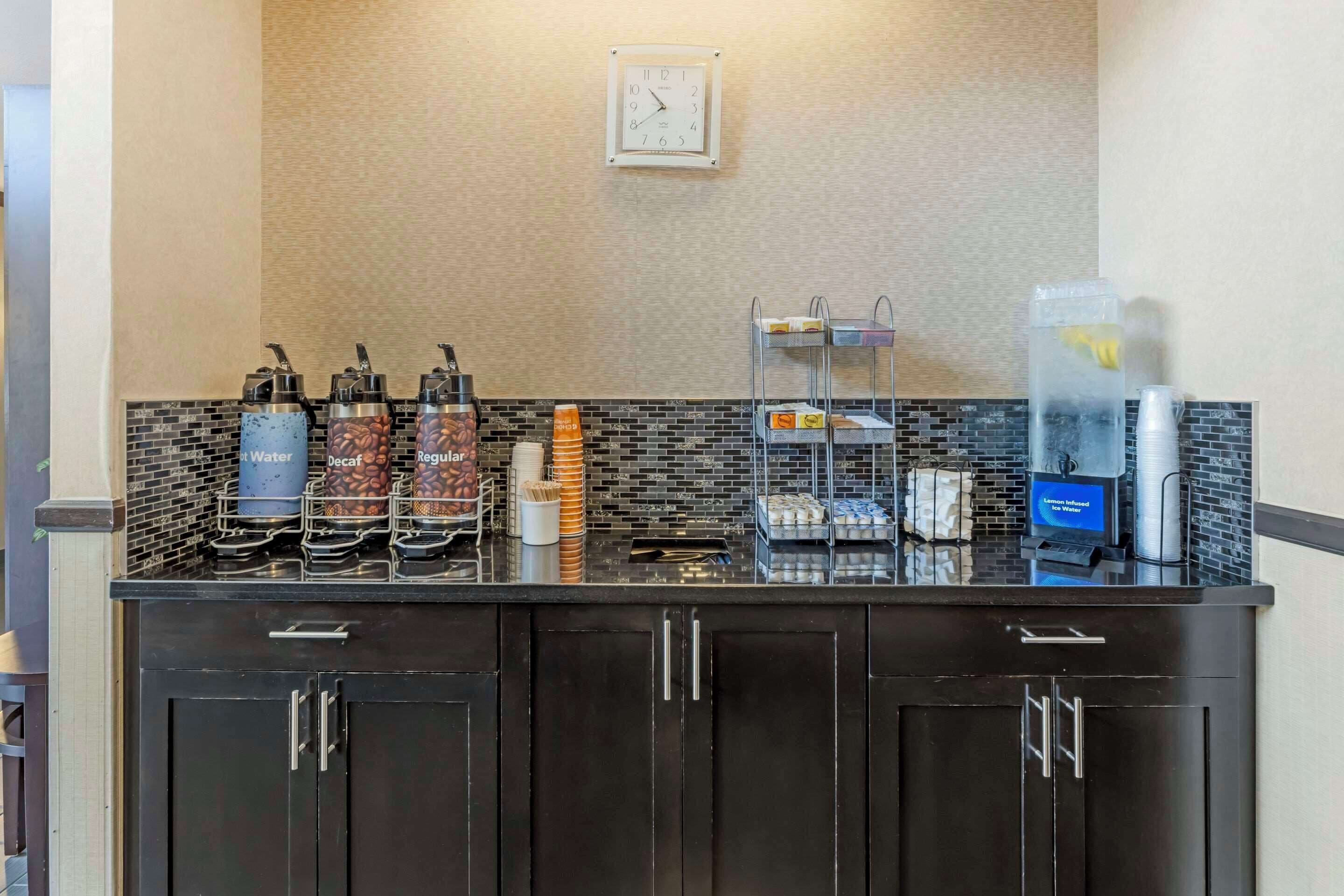 A coffee station with various coffee machines, a clock, and a water dispenser.