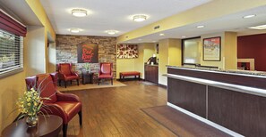 A hotel lobby with a reception desk, seating area with chairs, and a stone accent wall. - Red Roof Inn Washington DC - Columbia/ Fort Meade (Jessup)