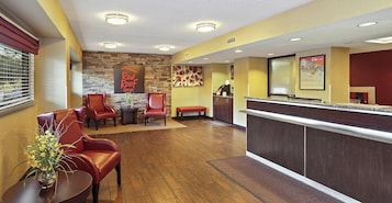 A hotel lobby with a reception desk, seating area with chairs, and a stone accent wall.