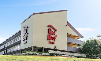 Edificio de Red Roof Inn con un diseño arquitectónico moderno, que presenta un llamativo letrero rojo y una estructura de dos pisos.