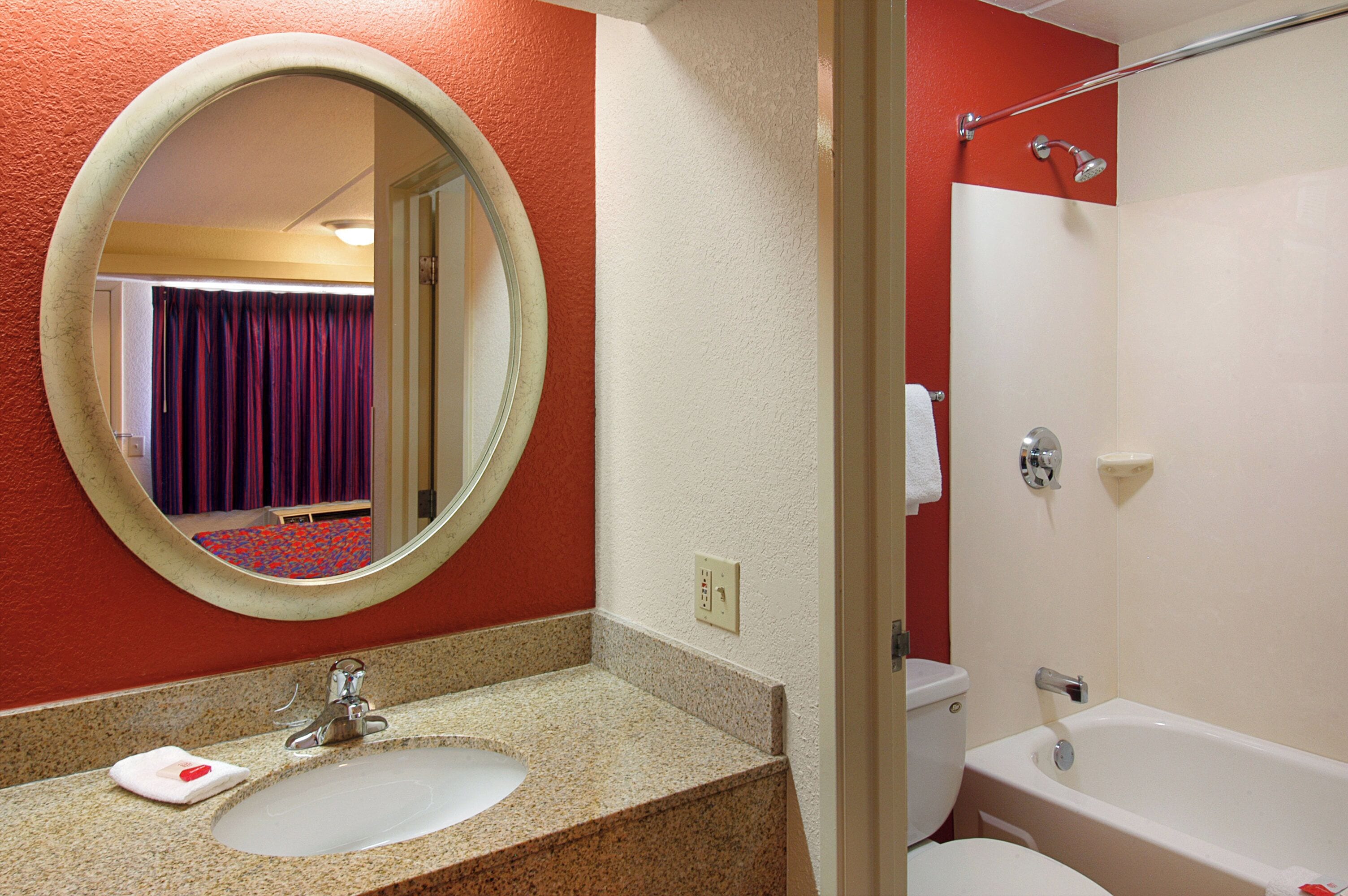 A bathroom with a sink, mirror, and bathtub.