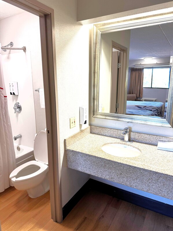 A bathroom with a toilet, sink, and mirror.