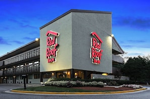 A Red Roof Inn with a modern architectural design, featuring a prominent neon sign and a well-maintained landscaped front yard. - Red Roof Inn Washington DC - Columbia/ Fort Meade (Jessup)