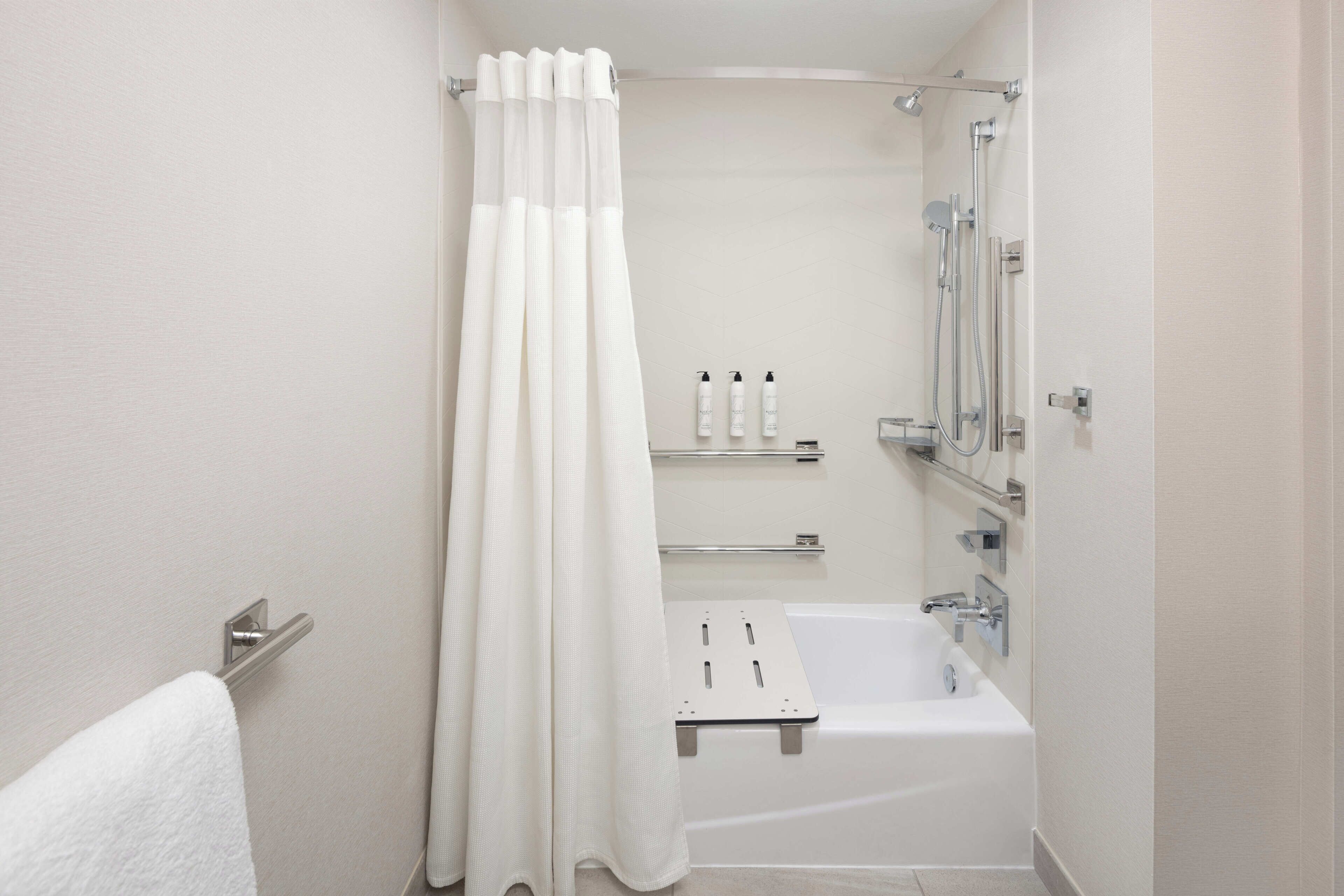 A modern bathroom with a bathtub, shower, and a towel rack.
