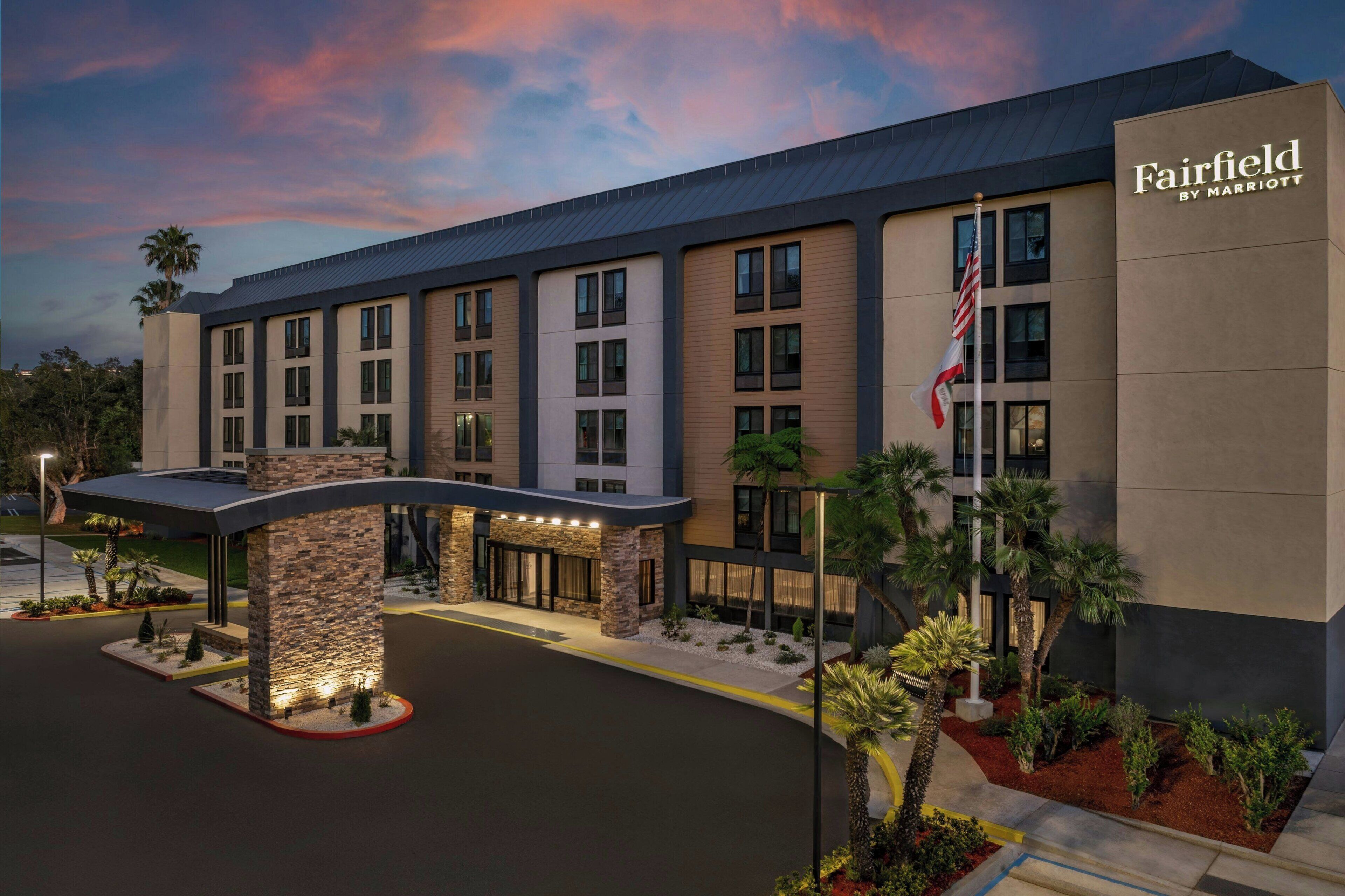A Fairfield by Marriott hotel with a modern design, featuring a covered entrance, multiple floors, and a flag.