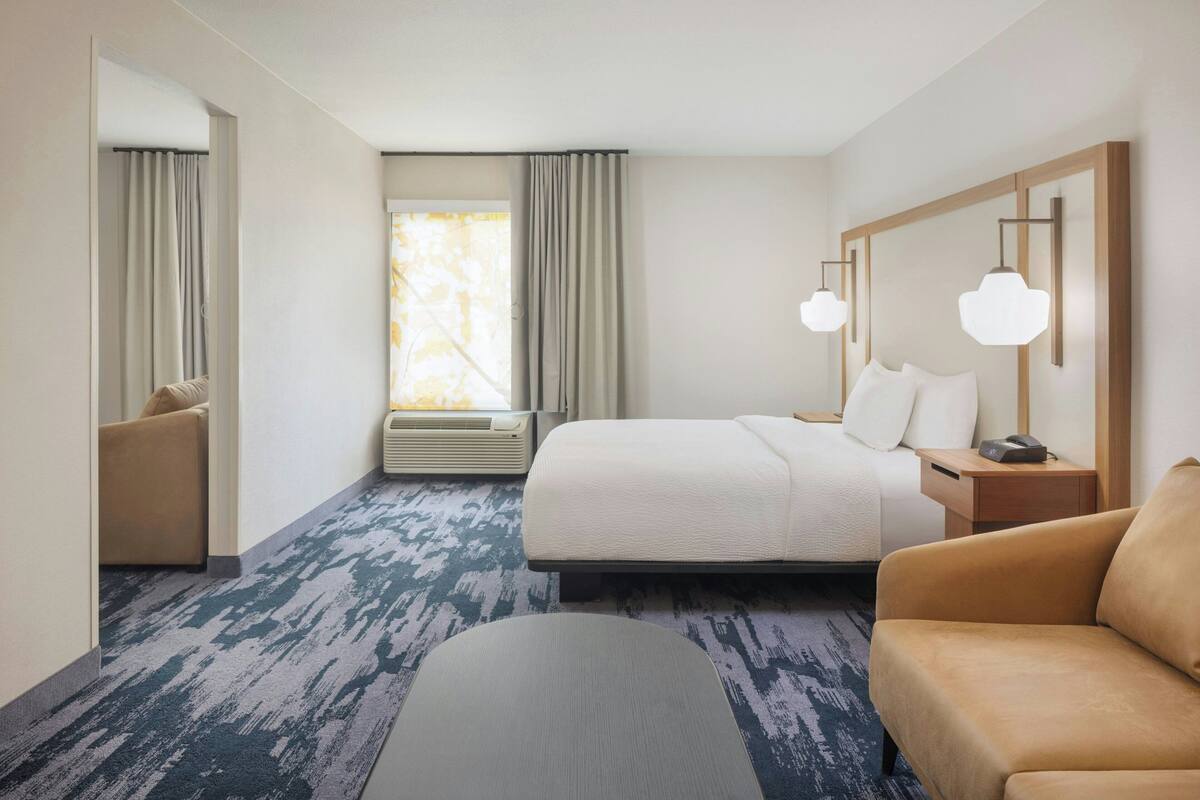 Ein Hotelzimmer mit Bett, Sofa, Schreibtisch und einem Fenster mit Vorhängen.