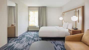 A hotel room with a bed, a sofa, a desk, and a window with curtains.