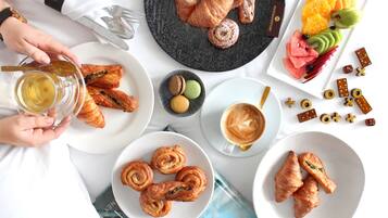 A table with pastries, fruit, and coffee, indicating a breakfast setting.