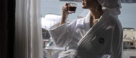 Una persona con bata blanca sentada junto a una ventana con vista al agua y edificios.