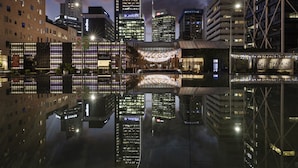 Ein nächtliches Stadtbild mit modernen Gebäuden und einem klaren Spiegelbild im Wasser.