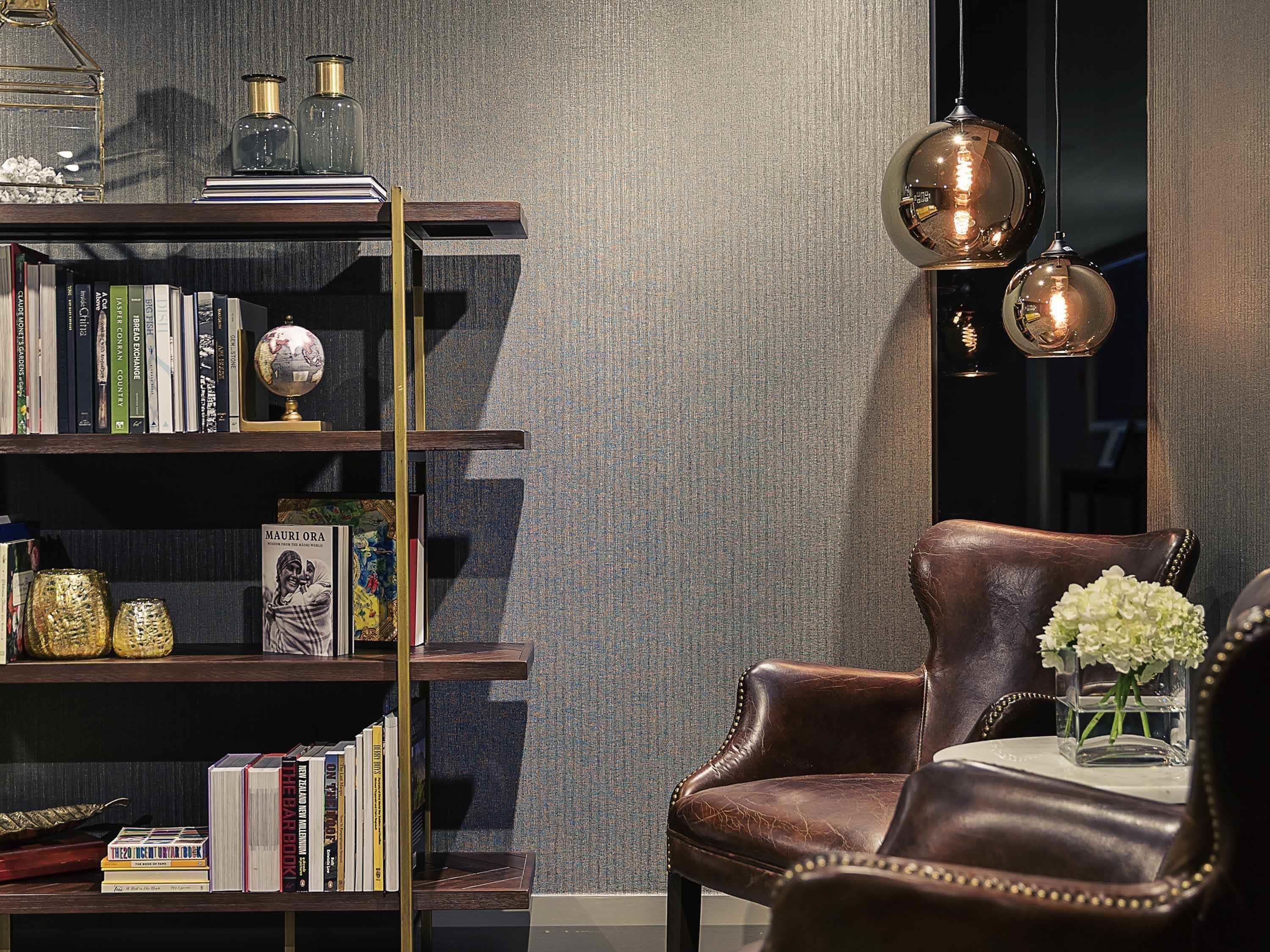 A well-organized room with a leather armchair, a bookshelf with books and decorative items, and a globe.