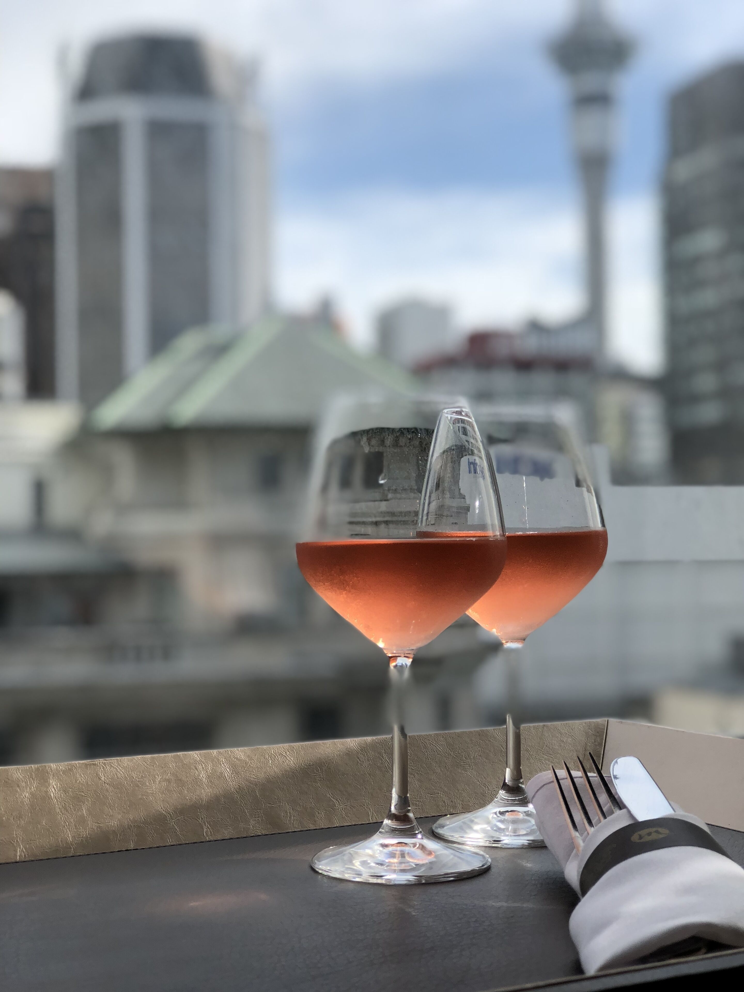 Two wine glasses on a table with a cityscape view in the background.