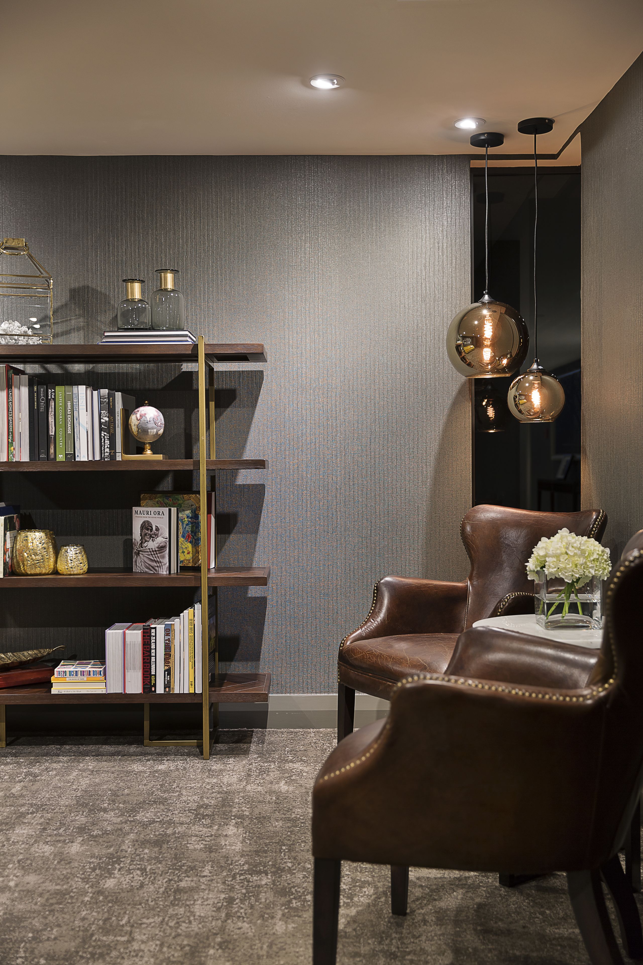A modern living room with a leather armchair, a bookshelf, and a globe.