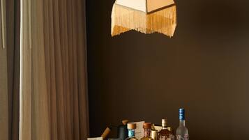 Quarto com armário de madeira, luminária pendente e mesa com garrafas e frutas.