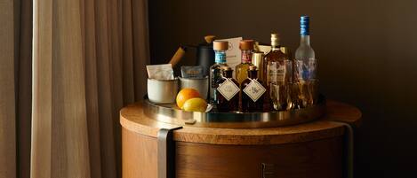 Een kamer met een houten kast, een hanglamp en een tafel met flessen en fruit.