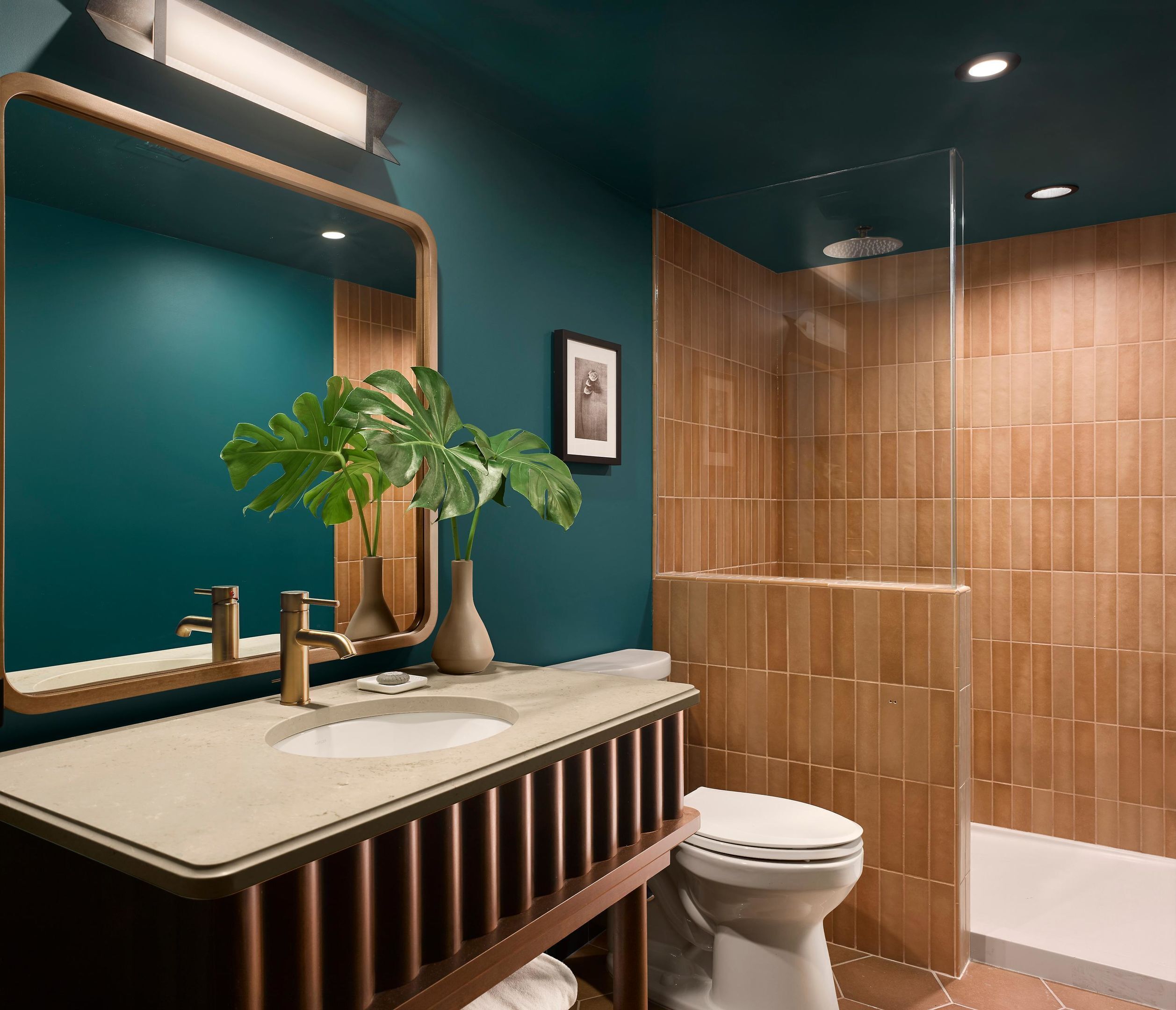A modern bathroom with a large mirror, two sinks, a toilet, and a shower area.