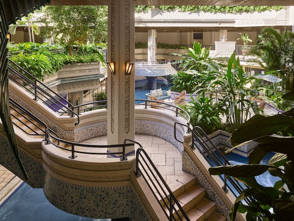 A multi-level indoor garden with a central fountain, surrounded by stairs and seating areas.