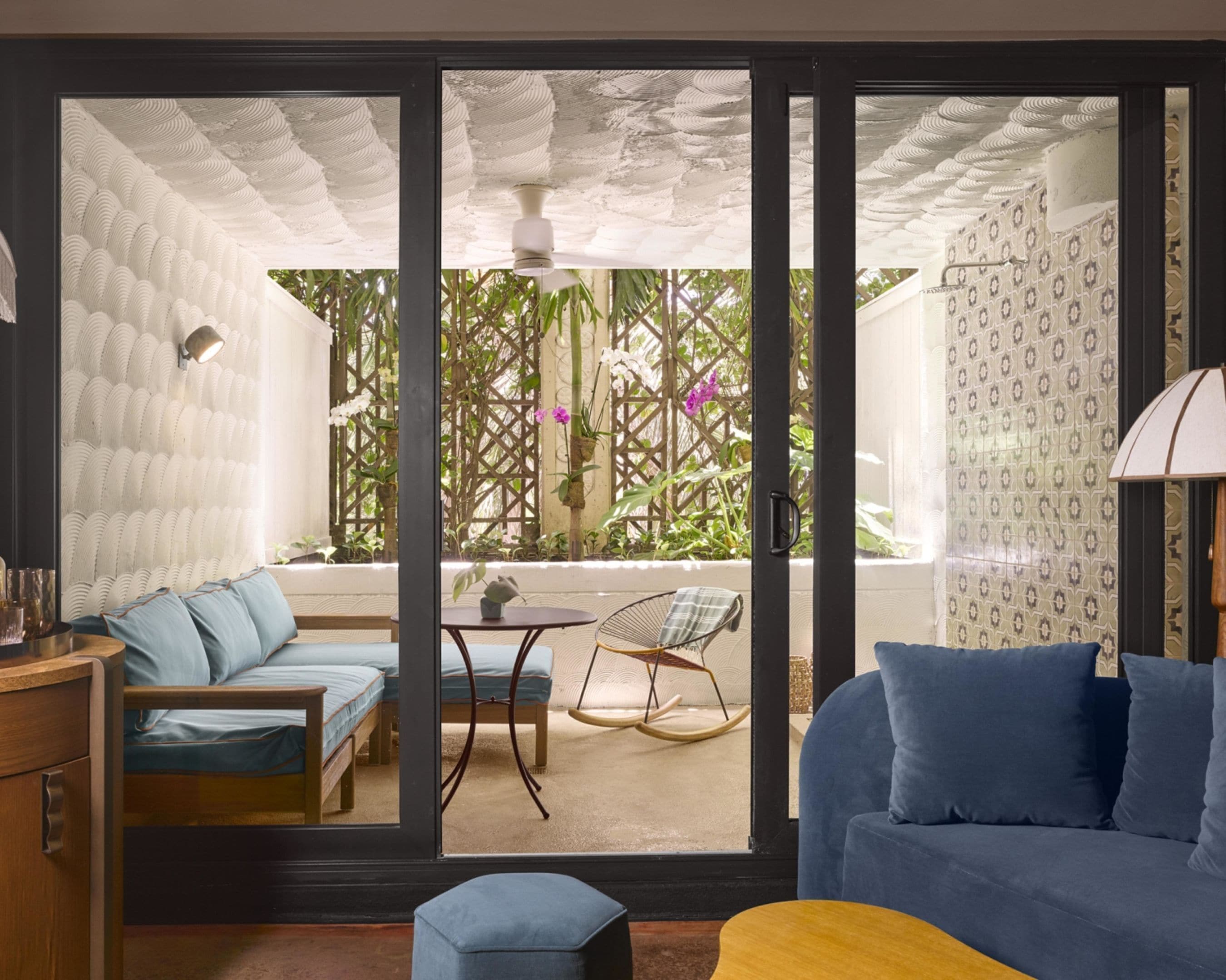 A room with a blue sofa, a wooden cabinet, a small table with a chair, and a swing chair.