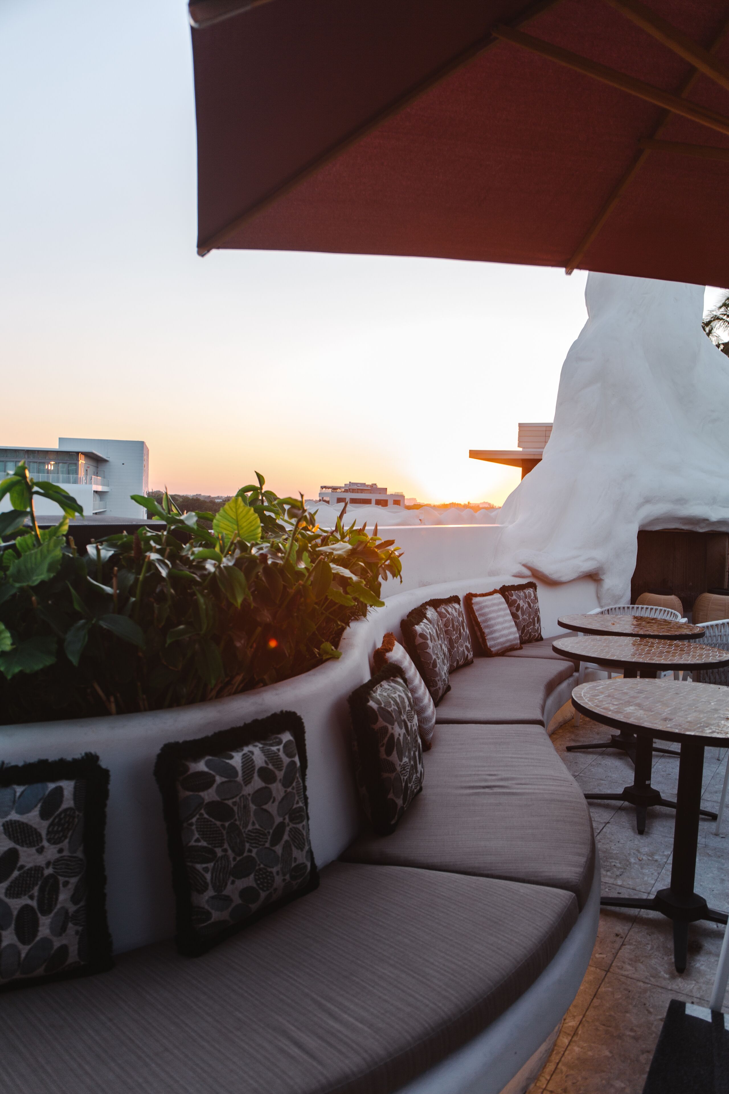 A rooftop terrace with a curved seating area, a table, and an umbrella.