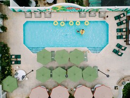 Una piscina al aire libre, sombrillas, sillones reclinables de piscina