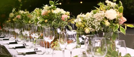 A long table set with wine glasses and floral centerpieces, likely for a formal event.