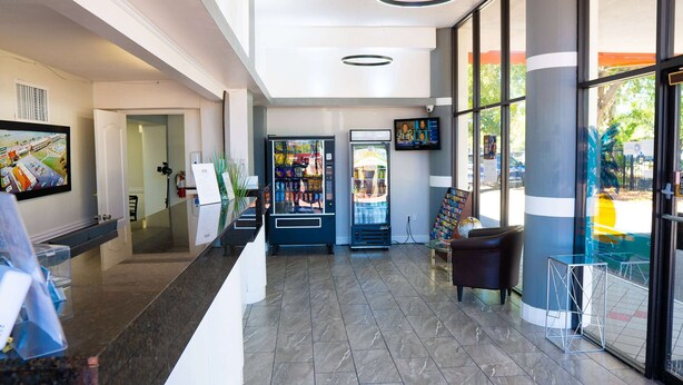 A hotel lobby with a reception desk, vending machines, a TV, and a large window.