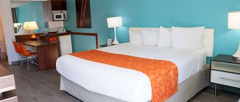 A hotel room with a bed, desk, chair, and a microwave.