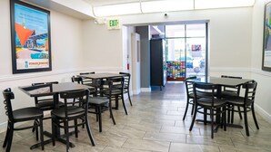 A restaurant interior with multiple tables and chairs, an exit sign, and a poster on the wall.